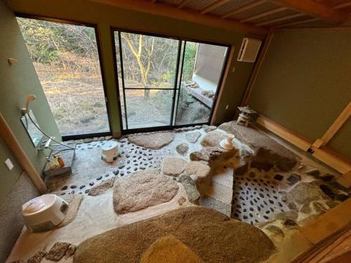 a bathroom with a large rock room with windows at 箱根温泉ヴィラ 源泉かけ流し bbq付き グループ宿泊に最適 in Hakone