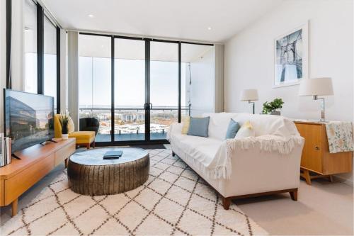 a living room with a white couch and a tv at 1-Bed with Amazing Views, Pool, Gym, BBQ & Parking in Canberra