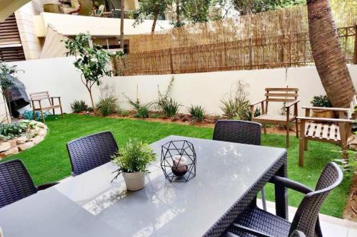 a patio with a table and chairs and a garden at Garden House By IsrApart in Ra‘ananna