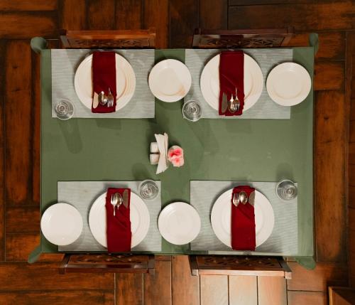 a table with white plates and red ties on it at Hotel Maenamla Namchi - yagi group in Namchi
