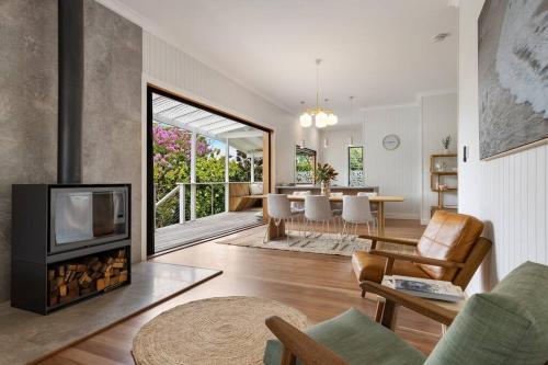 a living room with a fireplace and a dining room at Fuller Holidays - Daisy's Beach House - Burns St Byron Town in Byron Bay