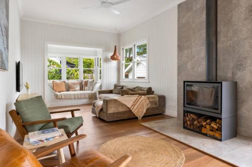 a living room with a fireplace and a couch at Fuller Holidays - Daisy's Beach House - Burns St Byron Town in Byron Bay