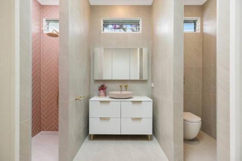 a bathroom with a sink and a toilet at Fuller Holidays - Daisy's Beach House - Burns St Byron Town in Byron Bay