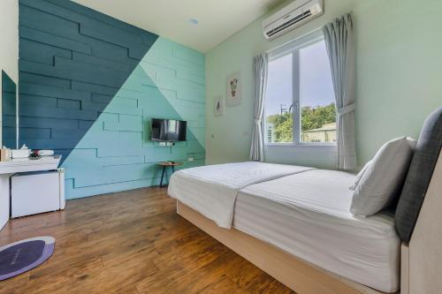 a bedroom with a bed and a blue wall at Bo Ya Homestay in Xiaoliuqiu