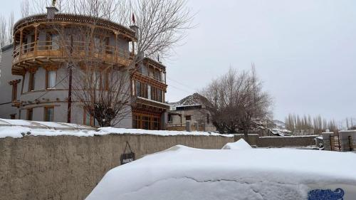 a snow covered yard with a house in the background at Dakpa House Ladakh in Ranbirpura
