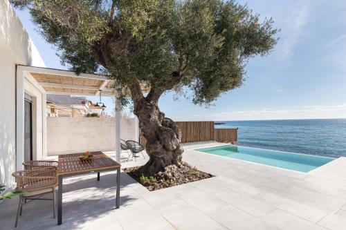 a patio with a tree and a swimming pool at Melivia Seafront Resort in Nea Skioni