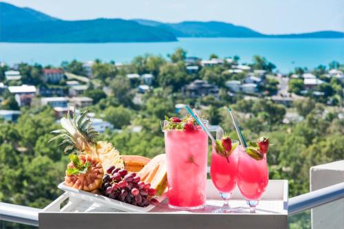 a table with two cocktails and fruit on a balcony at Oscar's View - Airlie Beach in Airlie Beach