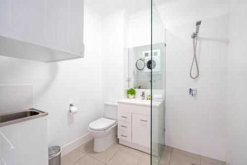 La salle de bains blanche est pourvue d'une douche et de toilettes. dans l'établissement Balmoral Apartment - Airy & Light-filled City Edge Comfort Stay, à Brisbane