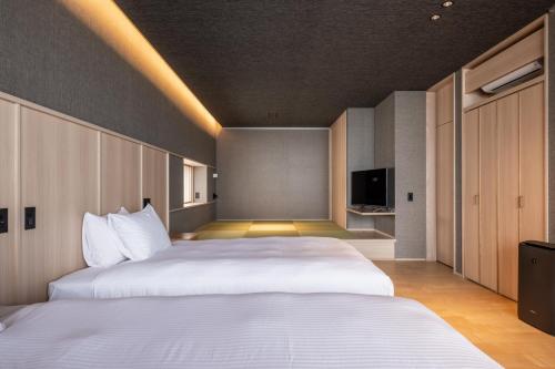 een hotelkamer met 2 bedden en een televisie bij Villa JacoO-ヴィラじゃこまる- in Sanuki