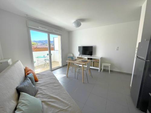 un salon avec un canapé et une table avec une télévision dans l'établissement Studio calme avec terrasse, proche centre-ville et plage, parking privé - FR-1-309-421, à Banyuls-sur-Mer