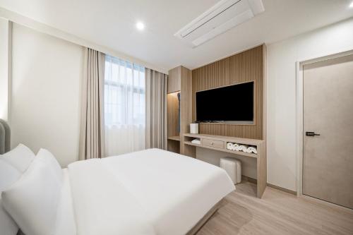 a hotel room with a bed and a television at Gyeongju Poverta Hotel in Gyeongju