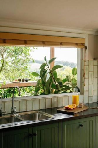 a kitchen counter with a sink and a window at The Honey Barn, Wabi-Sabi Cottage Byron Hinterland in Clunes