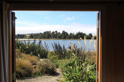 a view of a lake through a window at The Bird Hide - rustic luxury by the water in Dunedin