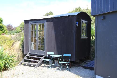 una casetta nera con tavolo e sedie di The Bird Hide - rustic luxury by the water a Dunedin