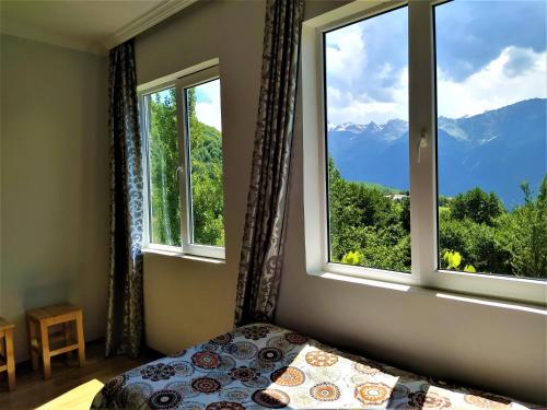 1 dormitorio con cama y ventana con vistas a las montañas en Gujejiani Guest house, en Mestia