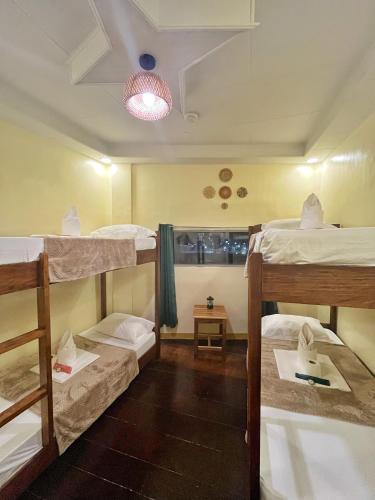a room with three bunk beds and a table at Cozy Coron Inn in San Nicolas