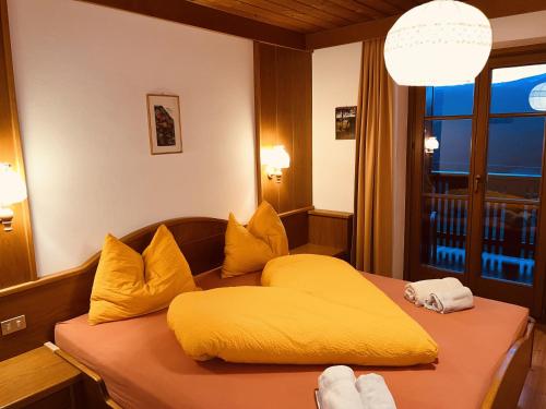 a yellow bed in a room with a window at Residence Zirmer Wohnung Wasser in Castelrotto
