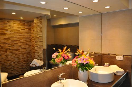 a bathroom with a sink and a mirror and flowers at Hotel Golf Internacional in Santa Teresita