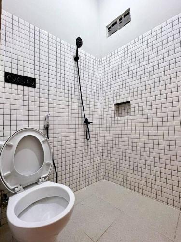 a white tiled bathroom with a toilet and a shower at AP Living Grand Kamala Lagoon Bekasi in Pekayon Satu
