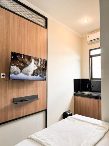 - une chambre avec un lit et une télévision murale dans l'établissement AP Living Grand Kamala Lagoon Bekasi, à Pekayon Satu