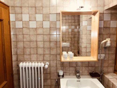 a bathroom with a sink and a mirror and a radiator at Residence Zirmer Wohnung Sonne in Kastelruth