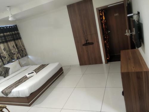 1 dormitorio con 1 cama y puerta de madera en Surbhi Hotel And Restaurant, en Rajkot