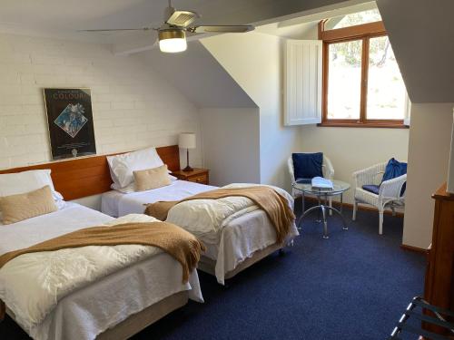a bedroom with two beds and a chair and a window at Girraween Country Inn in Ballandean