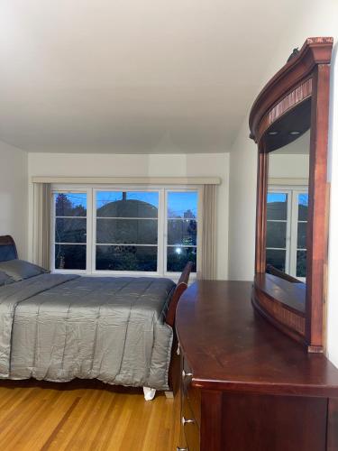 a bedroom with a bed and a dresser and windows at Home in West Vancouver in West Vancouver