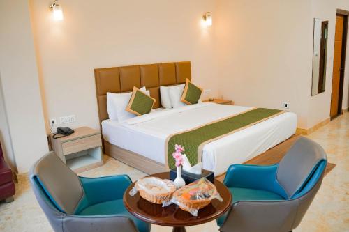a bedroom with a large bed with blue chairs and a table at Hotel Maenamla Namchi - yagi group in Namchi