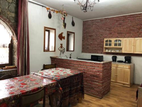 uma cozinha com uma mesa e uma parede de tijolos em Лилянината къща em Kalofer