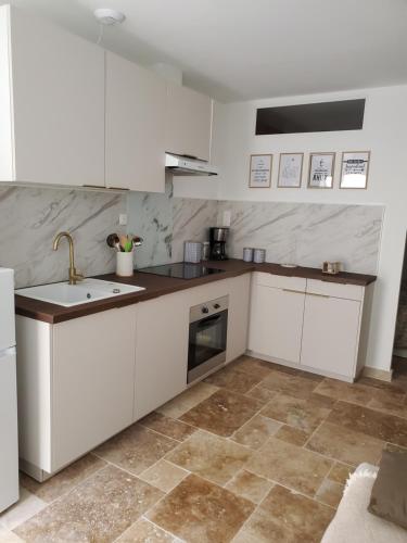 a kitchen with white cabinets and a sink at Harmonie in Monteux