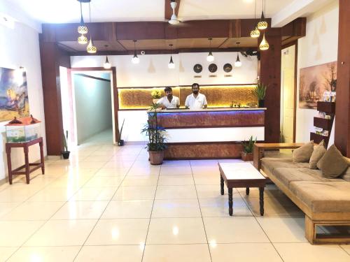 a lobby with a bar with two men in the kitchen at RAINBOW ROOMS in Kozhikode