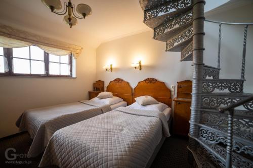 a bedroom with two beds and a staircase at Zagroda Kołodzieja in Zgorzelec