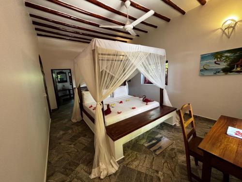 a bedroom with a bed with a canopy and a table at Villa Juliana in Jambiani