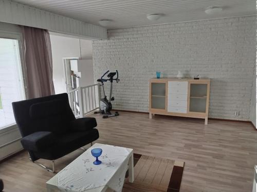 a living room with a black chair and a table at Talo 140 m2 in Siilinjärvi