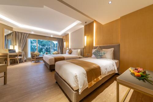 a hotel room with two beds and a desk at Glenmarie Hotel and Golf Resort in Shah Alam