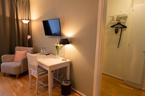 a room with a desk with a chair and a tv on the wall at Slottshotellet Annex in Kalmar