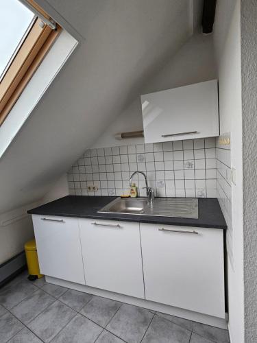 een keuken met witte kasten en een wastafel bij Appartement Cocooning in Roeschwoog