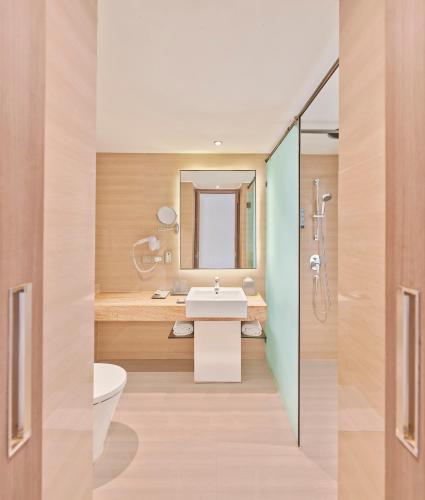 a bathroom with a sink and a toilet and a mirror at The Resort in Mumbai