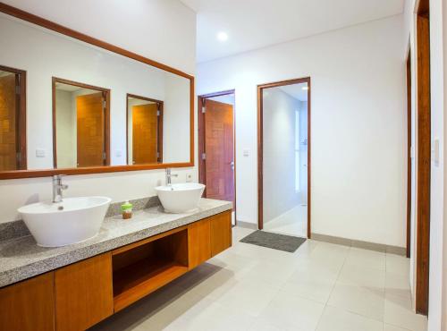 a bathroom with two sinks and two mirrors at Pudak Sari Unizou in Kuta