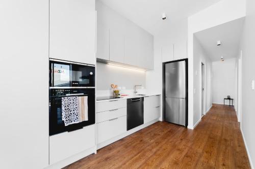惠靈頓的住宿－Brand new Wellington Central Apartments by CP collective，厨房配有白色橱柜和黑色冰箱。