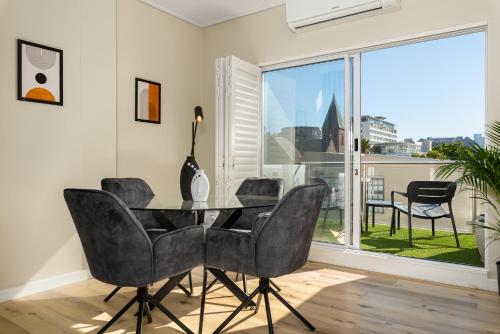 a dining room with a table and chairs and a large window at 220 On Loop Luxury Apartments in Cape Town