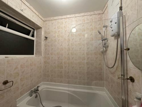 a bathroom with a shower and a bath tub at 4TH Studio Flat a Family Luxury London Home A Fully Equipped and furnished Studio With a King Size Bed And a Futon-Sofa Bed A Baby Cot A Kitchenette With a Private Toilet and Bath a Garden For up to 4 Guests and Free Parking in Lewisham