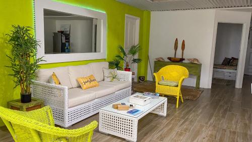 ein Wohnzimmer mit einer weißen Couch und gelben Stühlen in der Unterkunft ShineAwayHomes - Family Beach Front No air con in Rarotonga