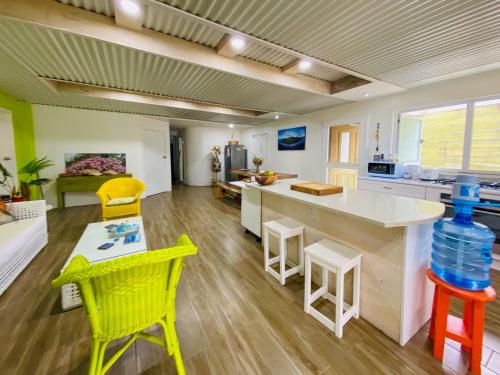 a kitchen with yellow chairs and a counter with a table at ShineAwayHomes - Family Beach Front central air con in Rarotonga