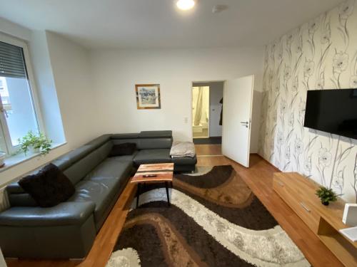 uma sala de estar com um sofá de couro preto e uma televisão de ecrã plano em Apartment bei Michael Bochum em Bochum