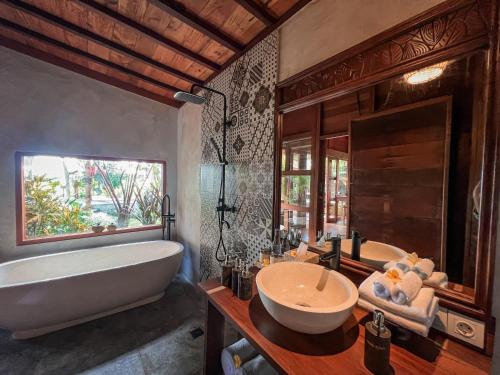 y baño con bañera, lavamanos y bañera. en Berlima Wooden Lodge by Pramana Villas en Ubud