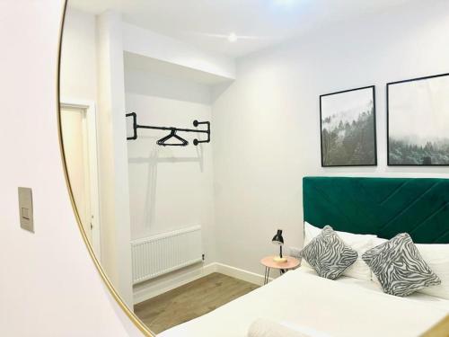 ein Spiegel mit einem Schlafzimmer mit einem weißen Bett und einem grünen Kopfteil in der Unterkunft Coastal Charm Comfort Home in Margate in Margate