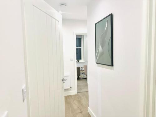 a hallway with a white door and a picture on the wall at Coastal Charm Comfort Home in Margate in Margate