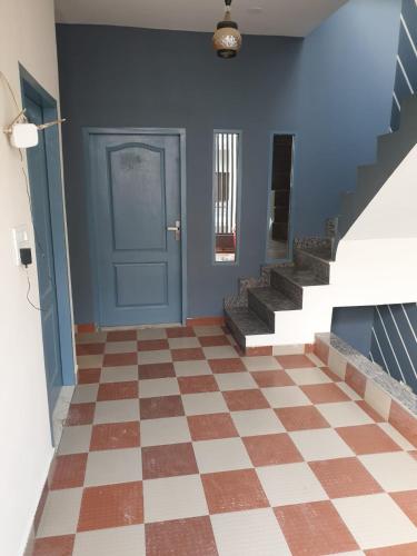 um corredor com uma porta azul e um piso xadrez em OLD SCHOOL em Phagwara